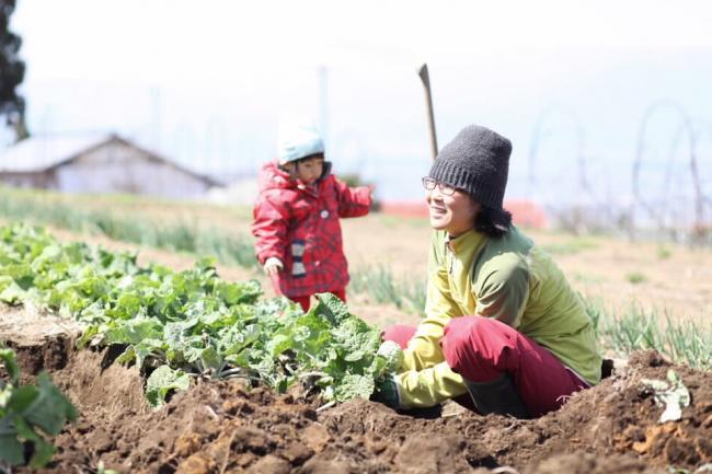子どもと畑仕事をする女性の写真